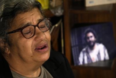 Laila Soueif, madre del activista prodemocracia encarcelado Alaa Abdel-Fattah, que agravó una huelga de hambre para pedir su puesta en libertad, habla durante una entrevista con The Associated Press junto a una foto de su hijo en su casa de El Cairo, Egipto, el jueves 10 de noviembre de 2022. Abdel-Fattah, ha vuelto a beber agua, según dijo su familia el lunes 14 de noviembre, en la primera comunicación del destacado disidente en más de una semana entre temores por su vida. (AP Foto/Amr Nabil)