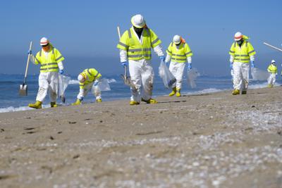 Trabajadores limpian una zona contaminada con un derrame de petróleo en la playa de Huntington, en California, el martes 5 de octubre de 2021. . (AP Foto/Ringo H.W. Chiu)