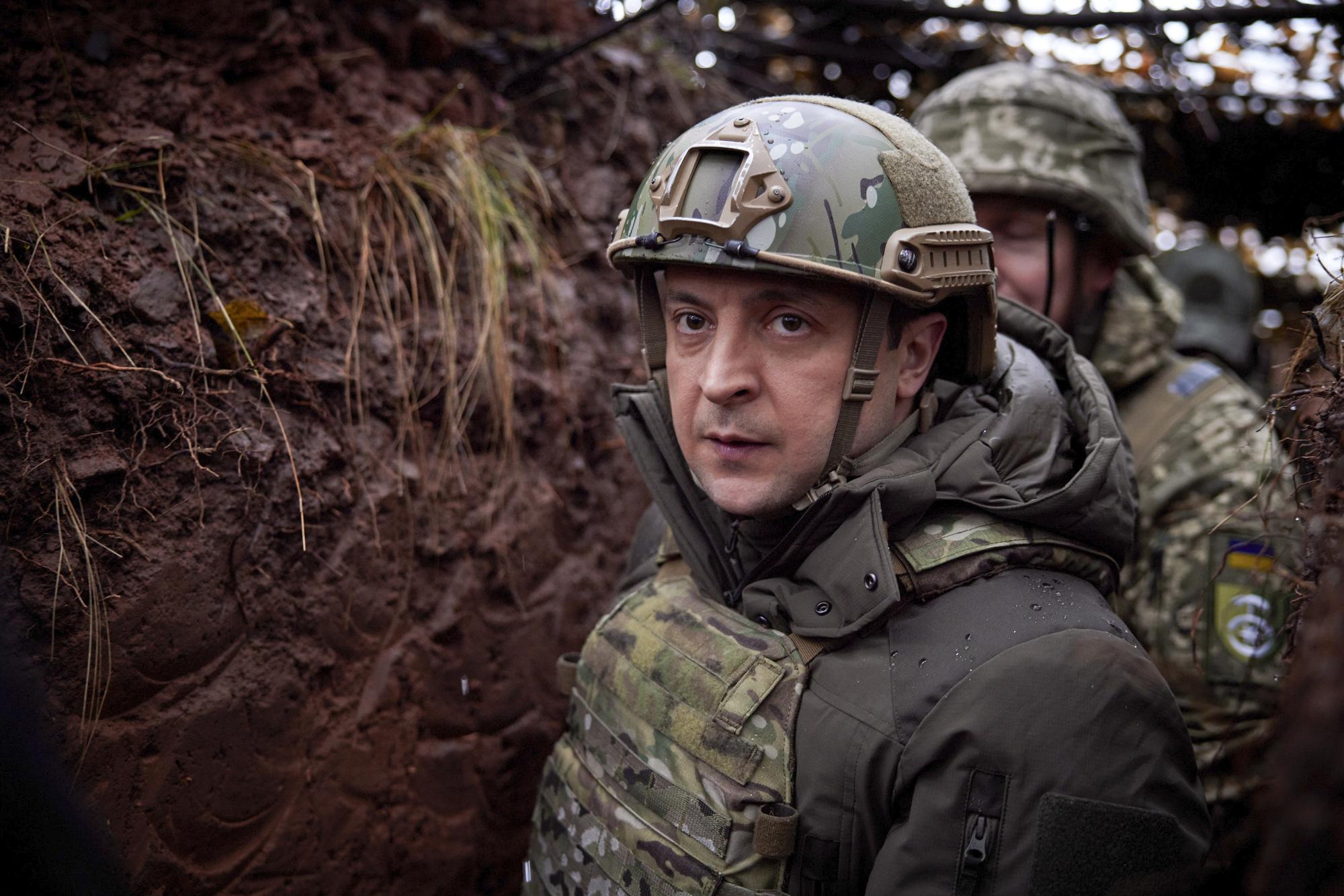 FILE - Ukrainian President Volodymyr Zelenskyy, walks under a camouflage net in a trench as he visits the war-hit Donetsk region, eastern Ukraine, Dec. 6, 2021. (Ukrainian Presidential Press Office via AP, File)