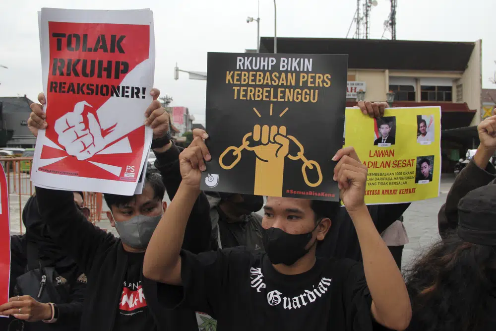 Activists hold up posters during a rally against Indonesia's new criminal law in Yogyakarta, Indonesia, Tuesday, Dec. 6, 2022. The country's parliament passed the long-awaited and controversial revision of its penal code Tuesday that criminalizes extramarital sex for citizens and visiting foreigners alike. Writings on the posters read "Reject the revised penal code" and "Revised criminal law shackles press freedom." (AP Photo/Slamet Riyadi)