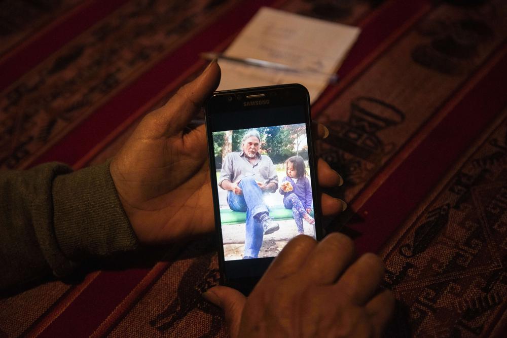Graciela Díaz muestra una foto de su esposo, Eduardo Rey con su nieta, en su casa de Montevideo, Uruguay, el miércoles 26 de mayo de 2021. (AP Foto/Matilde Campodonico)