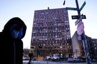 A person walks past an apartment building which suffered the city's deadliest fire in three decades, in the Bronx borough of New York, Tuesday, Jan. 11, 2022.  A malfunctioning electric space heater apparently started the fire Sunday in the 19-story building in the Bronx, fire officials said. (AP Photo/Matt Rourke)