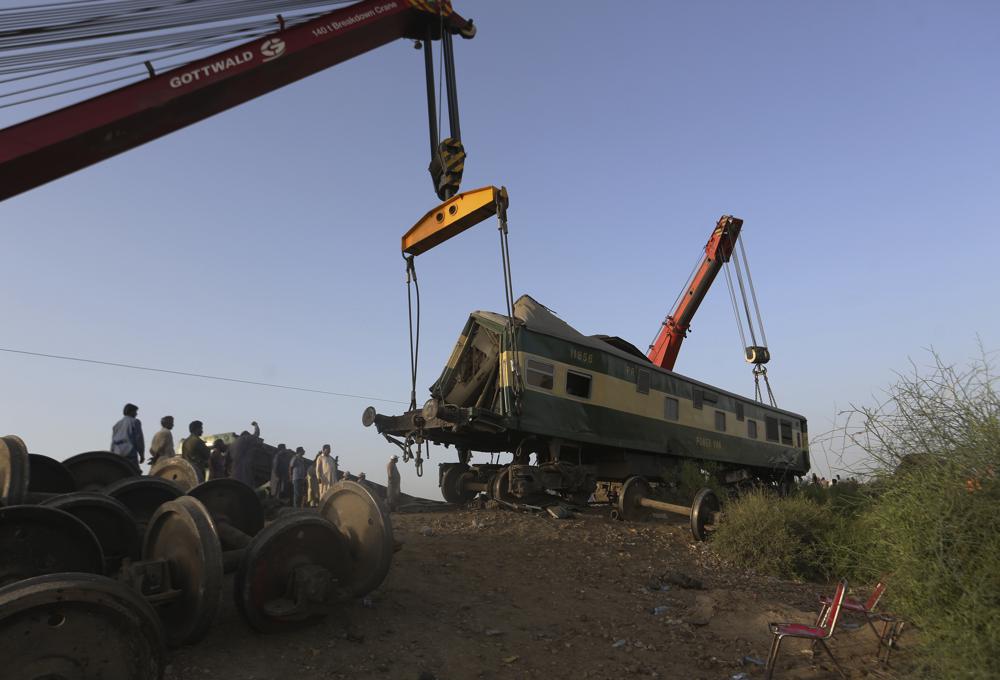 Railway workers use crane to remove wreckage to clear the track at the site of a train collision in the Ghotki district, southern Pakistan, Tuesday, June 8, 2021. The death toll from a deadly train accident in southern Pakistan jumped to dozens on Tuesday after rescuers pulled a dozen more bodies from crumpled cars of two trains that collided on a dilapidated railway track a day ago, an official said, as rescue work continued even 24 hours after the incident to find any survivors. (AP Photo/Fareed Khan)