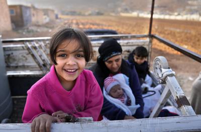 Una niña refugiada siria y su madre esperan en una camioneta cruzar la frontera a Siria en la ciudad fronteriza libanesa de Arsal, miércoles 26 de octubre de 2022. (AP Foto/Hussein Malla)