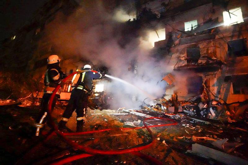 In this handout photo taken from video released by Ukrainian Police Department Press Service released on Friday, Feb. 25, 2022, firefighters hose down burning burning debris in front of a damaged building following a rocket attack on the city of Kyiv, Ukraine, Friday, Feb. 25, 2022. Russia is pressing its invasion of Ukraine to the outskirts of the capital. That comes a day after it unleashed airstrikes on cities and military bases and sent in troops and tanks from three sides. (Ukrainian Police Department Press Service via AP)