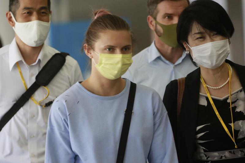 Belarusian Olympic sprinter Krystsina Tsimanouskaya, center, arrives at Narita International Airport in Narita, east of Tokyo Wednesday, Aug. 4, 2021. Tsimanouskaya plans to seek refuge in Europe after accusing team officials of trying to force her to leave the Tokyo Games early. (AP Photo/Koji Sasahara)