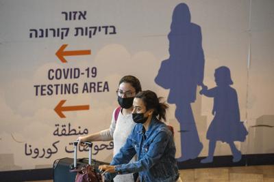 Dos viajeras con mascarillas llegan al aeropuerto Ben Gurion cerca de Tel Aviv, el domingo 28 de noviembre de 2021, en Israel. (AP Foto/Ariel Schalit)