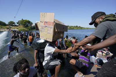 Haitian migrants use a dam to cross to and from the United States from Mexico, Friday, Sept. 17, 2021, in Del Rio, Texas. Thousands of Haitian migrants have assembled under and around a bridge in Del Rio presenting the Biden administration with a fresh and immediate challenge as it tries to manage large numbers of asylum-seekers who have been reaching U.S. soil. (AP Photo/Eric Gay)