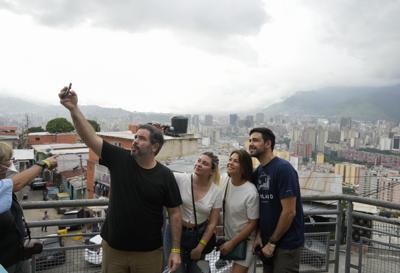 Turistas locales se toman una selfie durante un recorrido organizado por "Cumbe Tour" en el barrio San Agustín de Caracas, Venezuela, sábado 21 de agosto de 2021. Cumbe Tour trae a turistas, tanto nacionales como extranjeros, a San Agustín para mostrarles cómo viven los venezolanos de menores ingresos en lo que solía ser uno de los barrios más peligrosos de la ciudad. (Foto AP/Ariana Cubillos)