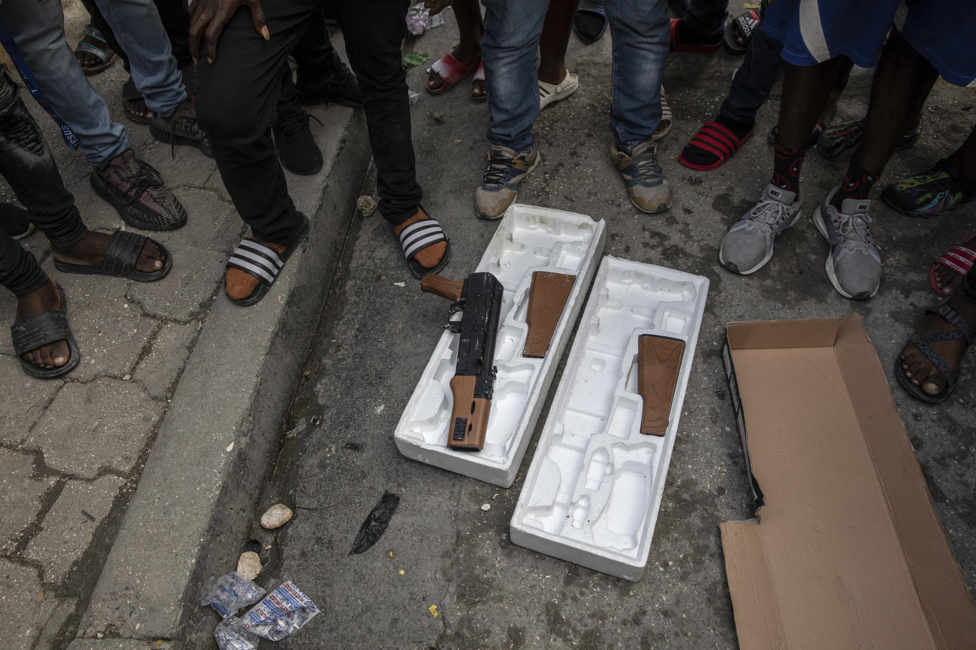 Protesters display toy guns used by musicians who were recording a music video the night before as they explain to journalists how police opened fire on the musicians killing one of them because police thought they were carrying real weapons, during a protest in downtown in Port-au-Prince, Haiti, Wednesday, Sept. 22, 2021. (AP Photo/Rodrigo Abd)