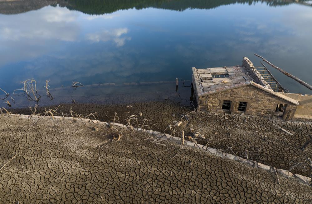 Una casa vieja, sumergida hace tres décadas cuando una presa hidroeléctrica inundó el valle, emerge debido a la sequía en el embalse de Lindoso, en el noroeste de España, el sábado 12 de febrero de 2022. Gran parte de España sufre una sequía extrema o prolongada, tras un invierno en el que ha llovido apenas un tercio de la media de los últimos años.(AP Foto/Emilio Morenatti)