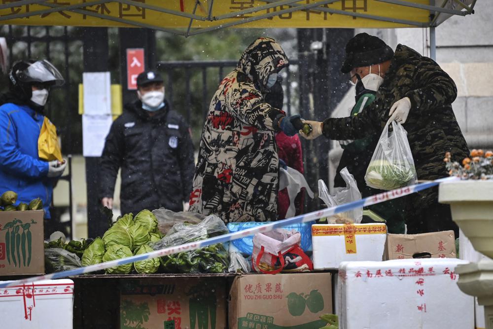 In this photo released by Xinhua News Agency, residents buy produce from a temporary market set up at the entrance of a quarantined residential area in Xi'an in northwestern China's Shaanxi Province on Dec. 25, 2021. Xi'an, which is about 1,000 kilometers (600 miles) southwest of Beijing, reported more than 300 new cases over the weekend, a sharp rise from previous days. The city of 13 million people has been locked down, with only one person per household allowed out every two days to shop for necessities. (Tao Ming/Xinhua via AP)