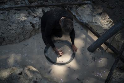 ARCHIVO - En esta fotografía de archivo del 21 de agosto de 2020, un minero utiliza un recipiente para separar fragmentos de oro de la tierra con agua en una mina ilegal en la selva amazónica, en la zona de Itaituba, estado de Pará, en Brasil. (AP Foto/Lucas Dumphreys, Archivo)