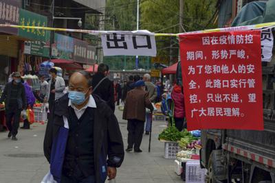 Un hombre con mascarilla camina al lado de un aviso que anuncia las políticas de tránsito en las calles como una medida de control pandémico en la ciudad de Lanzhou, en la provincia de Gansu del noroeste de China, el lunes 25 de octubre de 2021. (Chinatopix vía AP)
