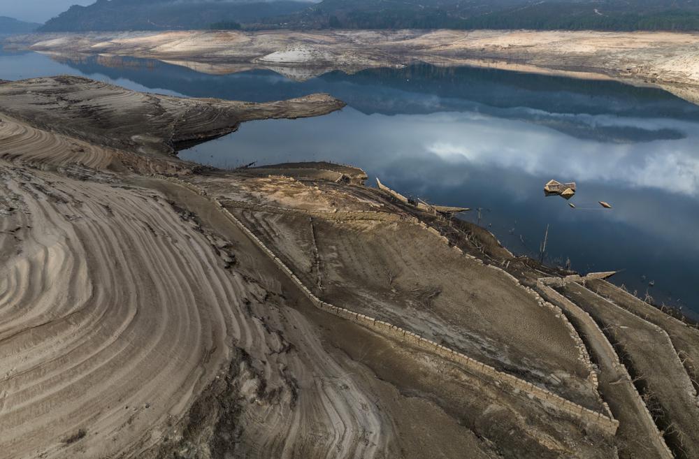 El tejado de una casa sumergida hace tres décadas cuando una presa hidroeléctrica inundó el valle, emerge debido a la sequía en el embalse de Lindoso, en el noroeste de España, el sábado 12 de febrero de 2022. Gran parte de España sufre una sequía extrema o prolongada, tras un invierno en el que ha llovido apenas un tercio de la media de los últimos años. (AP Foto/Emilio Morenatti)