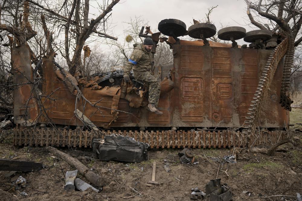 Un militar ucraniano salta de un vehículo de combate ruso destruido después de recolectar piezas y municiones en la aldea de Andriivka, Ucrania, gravemente afectada por los combates entre las fuerzas rusas y ucranianas, el miércoles 6 de abril de 2022. Varios edificios en la aldea quedaron reducidos a montículos de ladrillos y metal corrugado y los residentes luchan sin calefacción, electricidad o gas para cocinar.  (Foto AP/Vadim Ghirda)