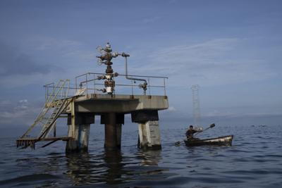 En esta imagen de archivo, un pescador pasa junto a una sonda de petróleo inactiva en el lago Maracaibo, en Venezuela, el 12 de octubre de 2022. (AP Foto/Ariana Cubillos, archivo)