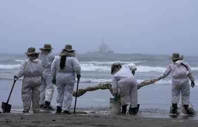 Un grupo de trabajadores continúa limpiando un derrame de petroleo en la playa Cavero, en el Callao, Perú, el sábado 22 de enero de 2022, causado por el oleaje que siguió a la erupcion submarina de un volcán en Tonga, en el Pacífico sur. (AP Foto/Martin Mejia)