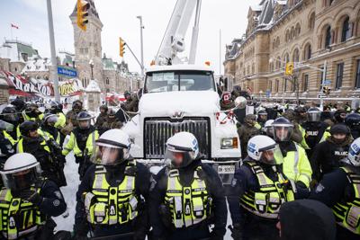La policía cuelga de un camión mientras las autoridades trabajan para poner fin a una protesta contra las medidas de COVID-19 en Ottawa, el sábado 19 de febrero de 2022. La policía hizo retroceder agresivamente a los manifestantes en la capital sitiada de Canadá el sábado, remolcando camiones, arrestando a docenas de manifestantes y finalmente retomando el control de las calles frente a los edificios del Parlamento del país. (Cole Burston /The Canadian Press vía AP)