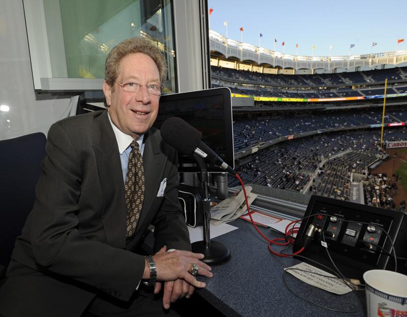 FILE - In this Sept. 25, 2009, file photo, New York Yankees broadcaster John Sterling sits in the booth before the Yankees' baseball game against the Boston Red Sox at Yankee Stadium in New York. Sterling was helped out of his flooding car by Spanish radio play-by-play man Rickie Ricardo on Wednesday night, Sept. 1, 2021, after Sterling got stuck trying to drive home after a game. Sterling and Ricardo both called New York's game at the Los Angeles Angels from Yankee Stadium because the radio crews have not resumed traveling with the team as part of COVID-19 protocols. (AP Photo/Bill Kostroun, File)