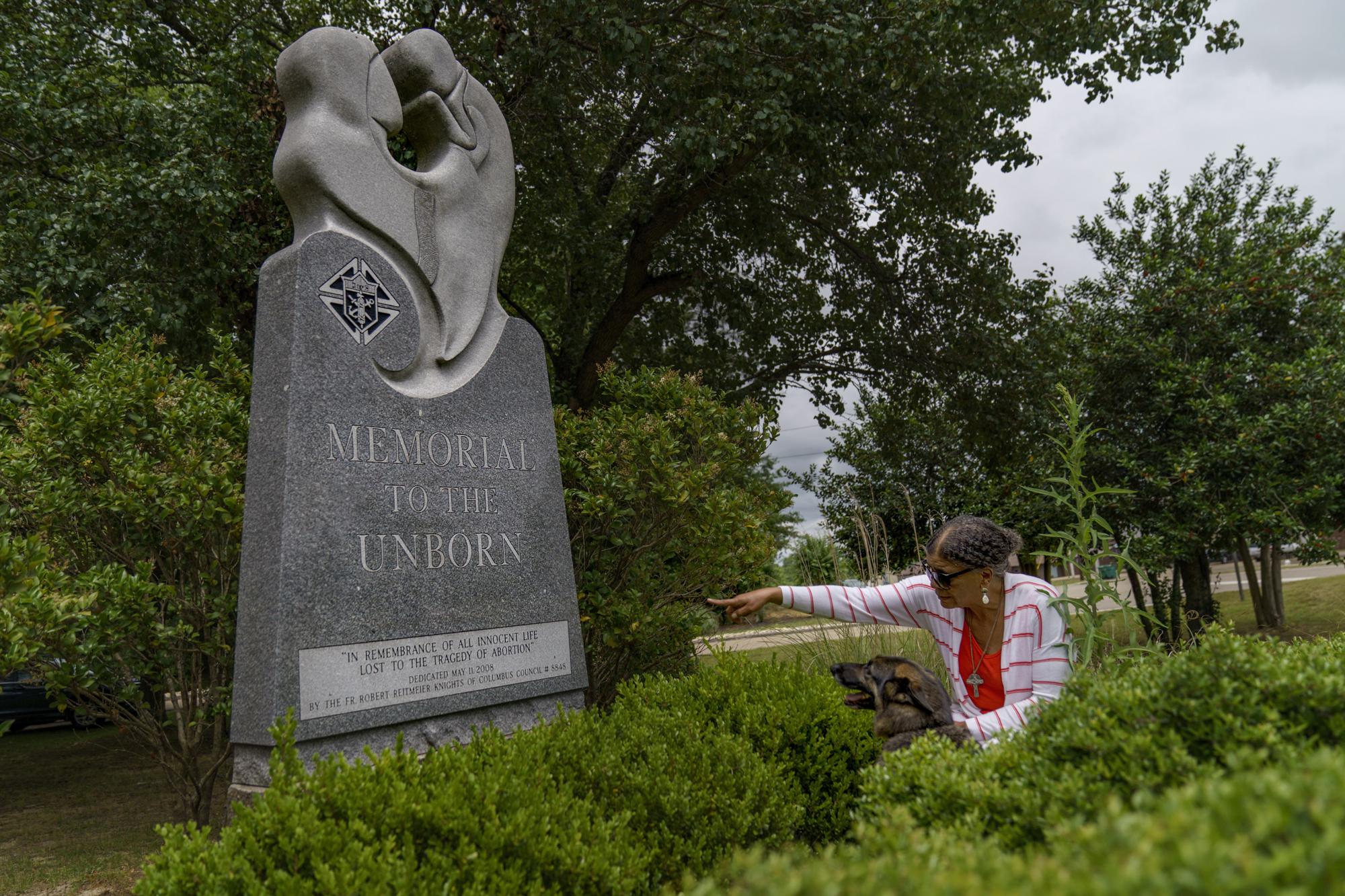 Tanya Britton le señala a su perra, Sybil, un monumento a los niños por nacer afuera de la iglesia católica St. James en Tupelo, Mississippi, el martes 24 de mayo de 2022. Britton tenía 19 años cuando abortó en 1972. ella durante años.  Encontró consuelo en las drogas y la negación.  Contempló el suicidio antes de aceptar lo que había hecho, tuvo un despertar espiritual y se dedicó a su activismo contra el aborto.  (Foto AP/David Goldman)