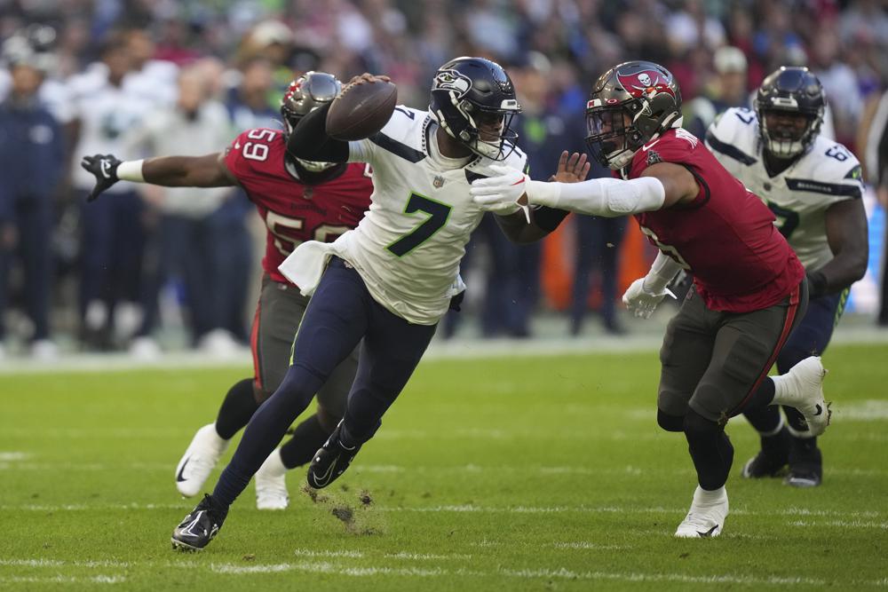 Seattle Seahawks quarterback Geno Smith (7) is sacked by Tampa Bay Buccaneers' Joe Tryon-Shoyinka (9) during the first half of an NFL football game, Sunday, Nov. 13, 2022, in Munich, Germany. (AP Photo/Matthias Schrader)