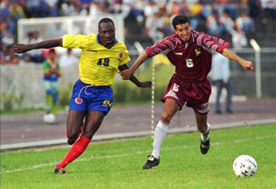 ARCHIVO - El futbolista colombiano Freddy Rincón, izquierda, lucha por el balón con el venezolano Elvis Martínez durante un partido de las eliminatorias sudamericanas para la Copa del Mundo Francia 1998, en San Cristóbal, Venezuela, el 15 de diciembre de 1996. Rincón, excapitán de la selección colombiana de fútbol, falleció a los 55 años tras resultar herido en un accidente automovilístico el lunes 11 de abril de 2022. (AP Foto/Jose Caruci, archivo)