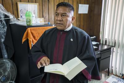 El juez Pablo Xitumul sostiene documentos relacionados con un caso mientras habla con un asistente dentro de su oficina antes de una audiencia en la Ciudad de Guatemala, el martes 5 de octubre de 2021. Xitimul, uno de los jueces más prominentes de Guatemala, enfrenta la posibilidad de perder su inmunidad, lo que abriría una larga lista de acciones legales iniciadas por familiares de personas a las que ha condenado en varios casos de alto perfil. (Foto AP/Moisés Castillo)