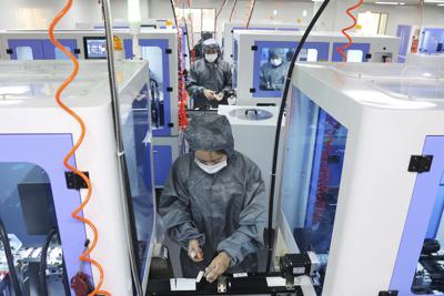 Employees work on the production line assembling diagnostic kits for SARS-CoV-2 (Covid-19) at a pharmaceutical factory in Nantong in eastern China's Jiangsu province Wednesday, Dec. 29, 2021. Chinese factory activity edged higher in December as supply disruptions eased and export demand weakened, a survey showed Friday. (Chinatopix Via AP)