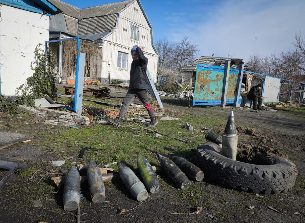 Un niño camina junto a proyectiles rusos sin explotar en el pueblo de Andriyivka cerca de Kiev, Ucrania, el lunes 11 de abril de 2022. Andriyivka fue ocupada por las tropas rusas al comienzo de la guerra entre Rusia y Ucrania y fue liberada recientemente por el ejército ucraniano.  (Foto AP/Efrem Lukatsky)