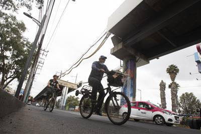 Dos ciclistas pasan el jueves 17 de junio de 2021 por el sitio donde una sección elevada de la Línea 12 del metro se desplomó a principios de mayo, en la Ciudad de México. (AP Foto/Marco Ugarte)