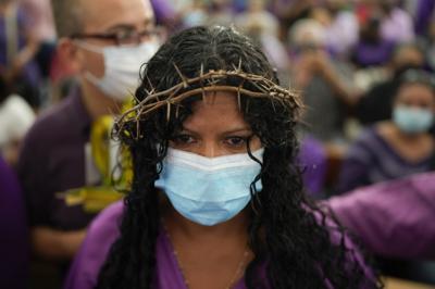 Una devota de una imagen de Jesús que lleva una cruz conocida como el Nazareno de San Pablo, con una corona de espinas y el color púrpura, reza dentro de la Basílica de Santa Teresa durante las celebraciones de Semana Santa en Caracas, Venezuela, el miércoles 13 de abril de 2022. (AP Foto/Ariana Cubillos)