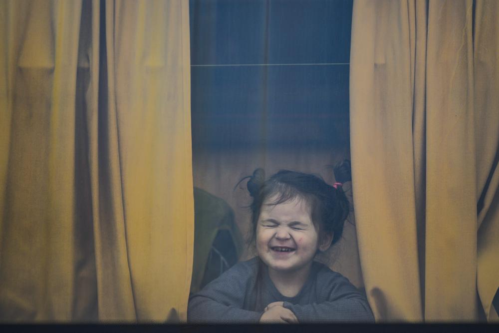 A child refugee fleeing the war from neighbouring Ukraine with her family grimaces as she sits in a bus after crossing the border by ferry at the Isaccea-Orlivka border crossing, in Romania, Friday, March 25, 2022. (AP Photo/Andreea Alexandru)