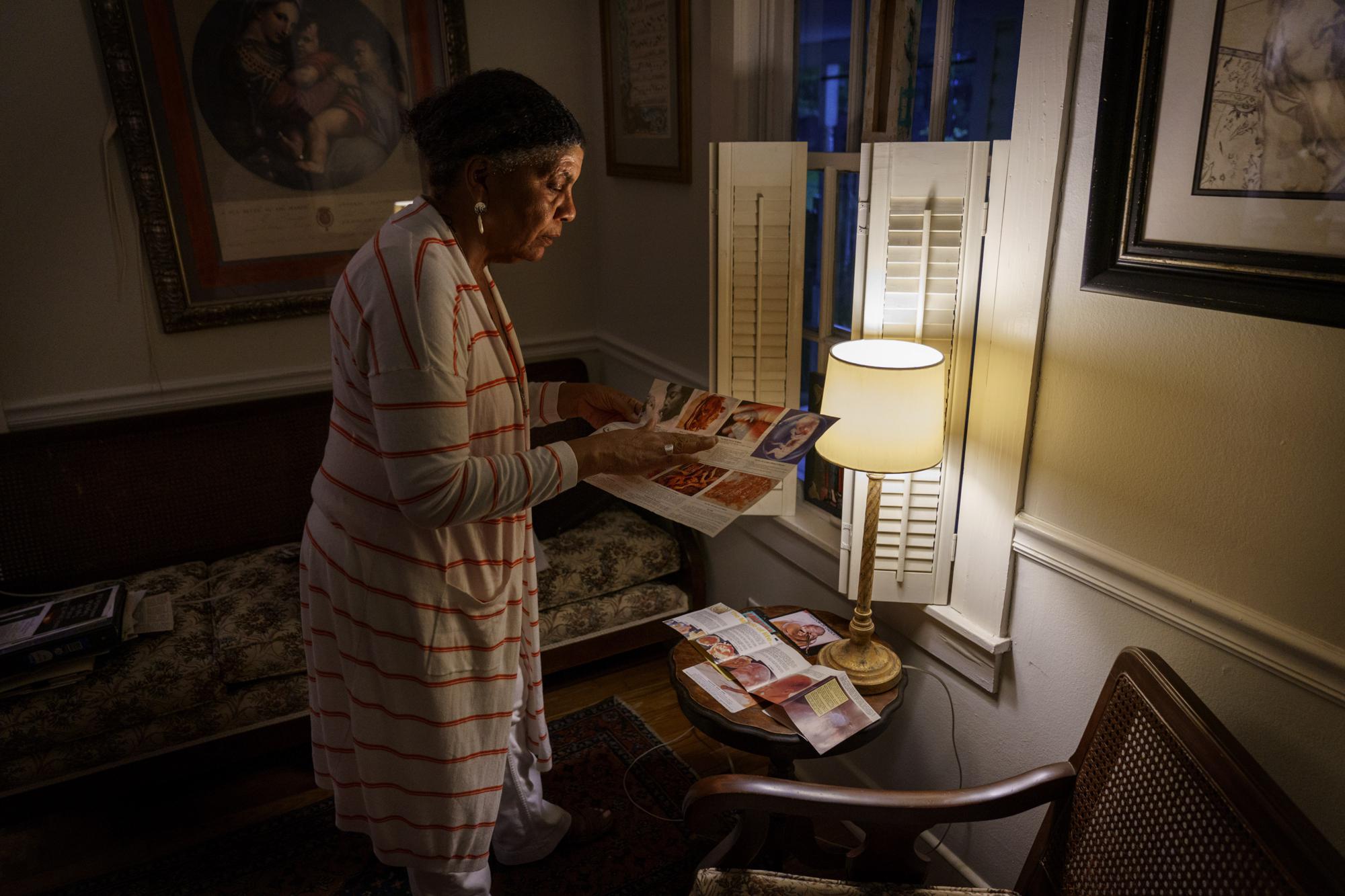 Tanya Britton looks over some of the fliers and pamphlets she used to hand out while protesting outside abortion clinics, Tuesday, May 24, 2022, as she stands in her home in Tupelo, Miss. "I've used every tactic that we have in our arsenal," she says. "You prepare. You practice. You know, you discipline yourself. You do all these things before you hit the battlefield." By her count, she's had seven arrests. (AP Photo/David Goldman)