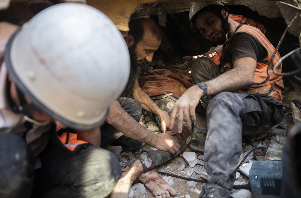 File - In this Sunday, May 16, 2021 file photo, Palestinian rescuers pull a body of a woman of al-Kawlak family from under the rubble of one of the destroyed residential buildings following deadly Israeli airstrikes in Gaza City. The single deadliest bombing raid of Israel's fourth war with Hamas collapsed two apartment buildings and killed 22 members of the extended al-Kawlak family, including a 6-month-old boy and his 89-year-old great-grandfather (AP Photo/Khalil Hamra,File)