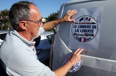 Un hombre coloca un cartel con la frase "La caravana de la libertad" en una camioneta antes de partir hacia París, en Bayona, en el suroeste de Francia, el miércoles 9 de febrero de 2022. (AP Foto/Bob Edme)