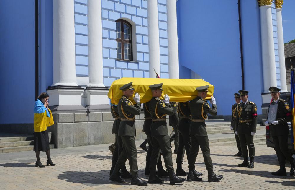 Los soldados llevan un ataúd con los restos de un soldado voluntario Oleksandr Makhov, un conocido periodista ucraniano, asesinado por las tropas rusas, en la catedral de San Miguel en Kiev, Ucrania, el lunes 9 de mayo de 2022. El ataúd es seguido por la viuda de Makhov. (Foto AP/Efrem Lukatsky)