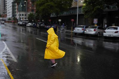 Una mujer cruza una calle durante la lluvia en Caracas, Venezuela, el miércoles 29 de junio de 2022, en momentos en que una tormenta afecta el sur del Caribe y el norte de Sudamérica. (AP Foto/Ariana Cubillos)