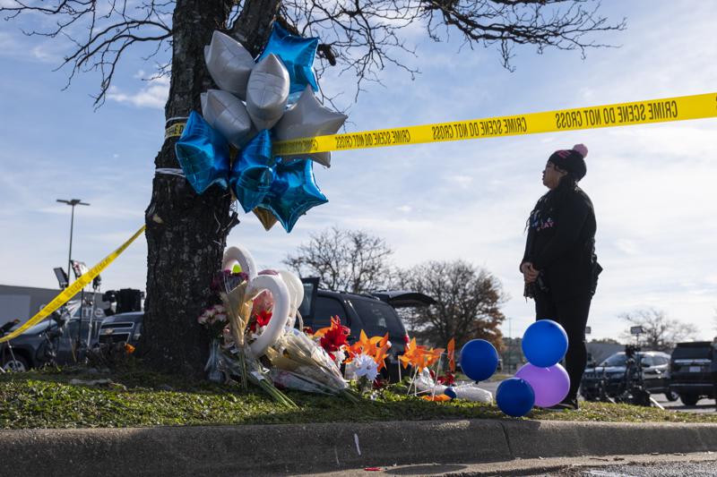 Mary Chatkovsky places balloons and flowers on a memorial outside of the Chesapeake, Va., Walmart on Thursday, Nov. 24, 2022.  Andre Bing, a Walmart manager, opened fire on fellow employees in the break room of the Virginia store, killing six people in the country’s second high-profile mass shooting in four days, police and witnesses said Wednesday. (Billy Schuerman/The Virginian-Pilot via AP)