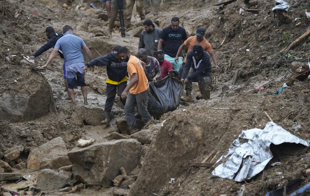 Residentes y voluntarios recuperan el cuerpo de una persona fallecida en un deslave, en Petrópolis, Brasil, el 16 de febrero de 2022. (AP Foto/Silvia Izquierdo)