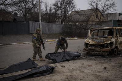 Soldados ucranianos recuperan los restos de cuatro civiles de un vehículo calcinado en Bucha, a las afueras de Kiev, Ucrania, el martes 5 de abril de 2022. (AP Foto/Felipe Dana)