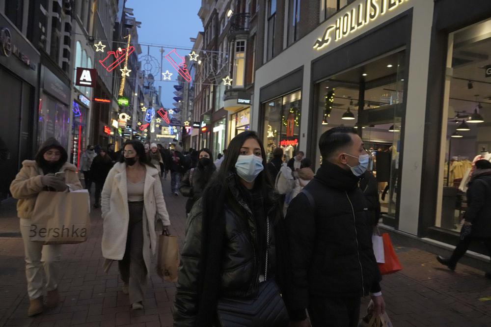 People walk down a street in Amsterdam, the Netherlands, Saturday, Dec. 18, 2021. Dutch government ministers are meeting Saturday to discuss advice from a panel of experts who are reportedly advising a toughening of the partial lockdown that is already in place to combat COVID-19. (AP Photo/Peter Dejong)