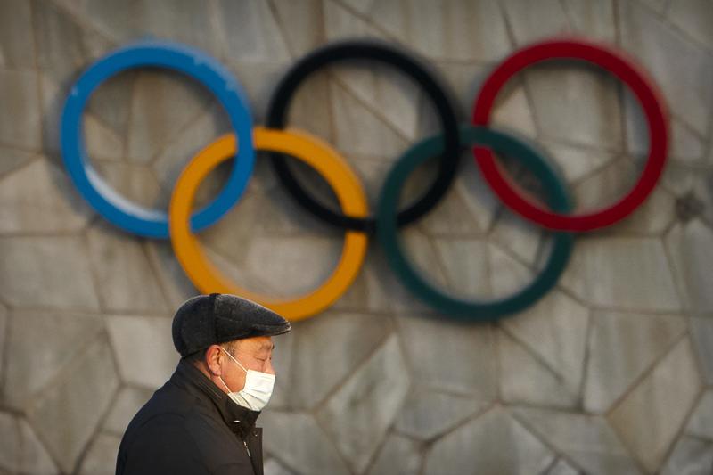 FILE - A man walks past the Olympic rings on the exterior of the National Stadium, also known as the Bird's Nest, which will be a venue for the upcoming 2022 Winter Olympics, in Beijing, Tuesday, Feb. 2, 2021. Making an Olympic team is hard enough. This winter, those who earn their spots on the U.S. squad will find it takes even more work to get to Beijing.  (AP Photo/Mark Schiefelbein, File)