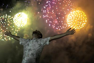 Un hombre celebra el inicio del año nuevo bajo el cielo iluminado por fuegos artificiales, en la playa de Copacabana, en Río de Janeiro, Brasil, el 1 de enero de 2022. (AP Foto/Bruna Prado)