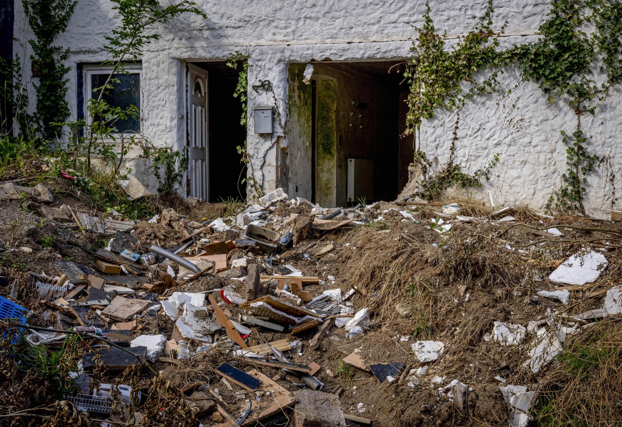 Debris from last year's flood sits in front of a destroyed house in the village of Schuld in the Ahrtal valley, Germany, Tuesday, July 5, 2022. Floods caused by heavy rain hit the region on July 14, 2021 causing the death of about 130 people. (AP Photo/Michael Probst)
