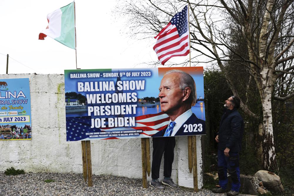 Ray Clarke, a la izquierda, y Eddie Ruane colocaron banderas en Ballina, Irlanda, el martes 4 de abril de 2023. La emoción crece en Ballina, una pequeña ciudad irlandesa que fue hogar de algunos de los antepasados ​​del presidente Joe Biden.  Biden tiene previsto visitar la ciudad la próxima semana, como parte de un viaje de cuatro días a Irlanda y la vecina Irlanda del Norte.  (Foto AP/Peter Morrison)