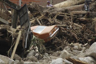 Un auto, entre los restos arrastrados por una inundación y deslaves provocados por las lluvias torrenciales en el municipio de Tovar, en el estado de Mérida, Venezuela, el 26 de agosto de 2021. (AP Foto/Luis Bustos)