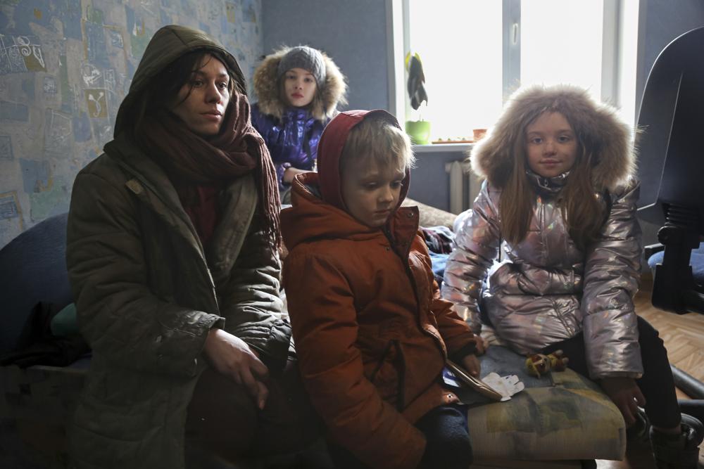 A woman and her children speak to journalists sitting in their flat without electricity on the territory which is under the Government of the Donetsk People's Republic control, on the outskirts of Mariupol, Ukraine, Thursday, March 24, 2022. (AP Photo/Alexei Alexandrov)