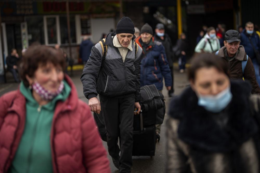 People drag their suitcases as they arrive in a bus station to leave Kyiv, Ukraine, Thursday, Feb. 24, 2022. (AP Photo/Emilio Morenatti)