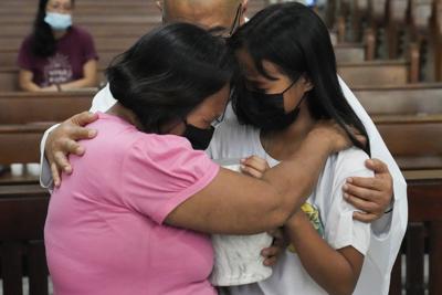 El sacerdote Flaviano "Flavie" Villanueva consola a familiares mientras reciben la urna que contiene los restos de víctimas de asesinatos extrajudiciales en una iglesia en la ciudad de Quezon, Filipinas, el miércoles 28 de septiembre de 2022. (AP Foto/Aaron Favila)